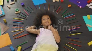 漂亮的非裔美国小女孩躺在地板上，计划未来的假期